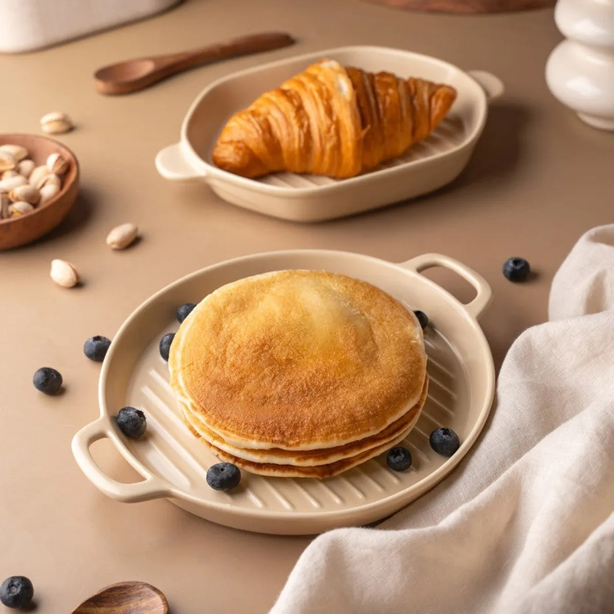 Ivory round and hexagon platters serving pancakes and a croissant