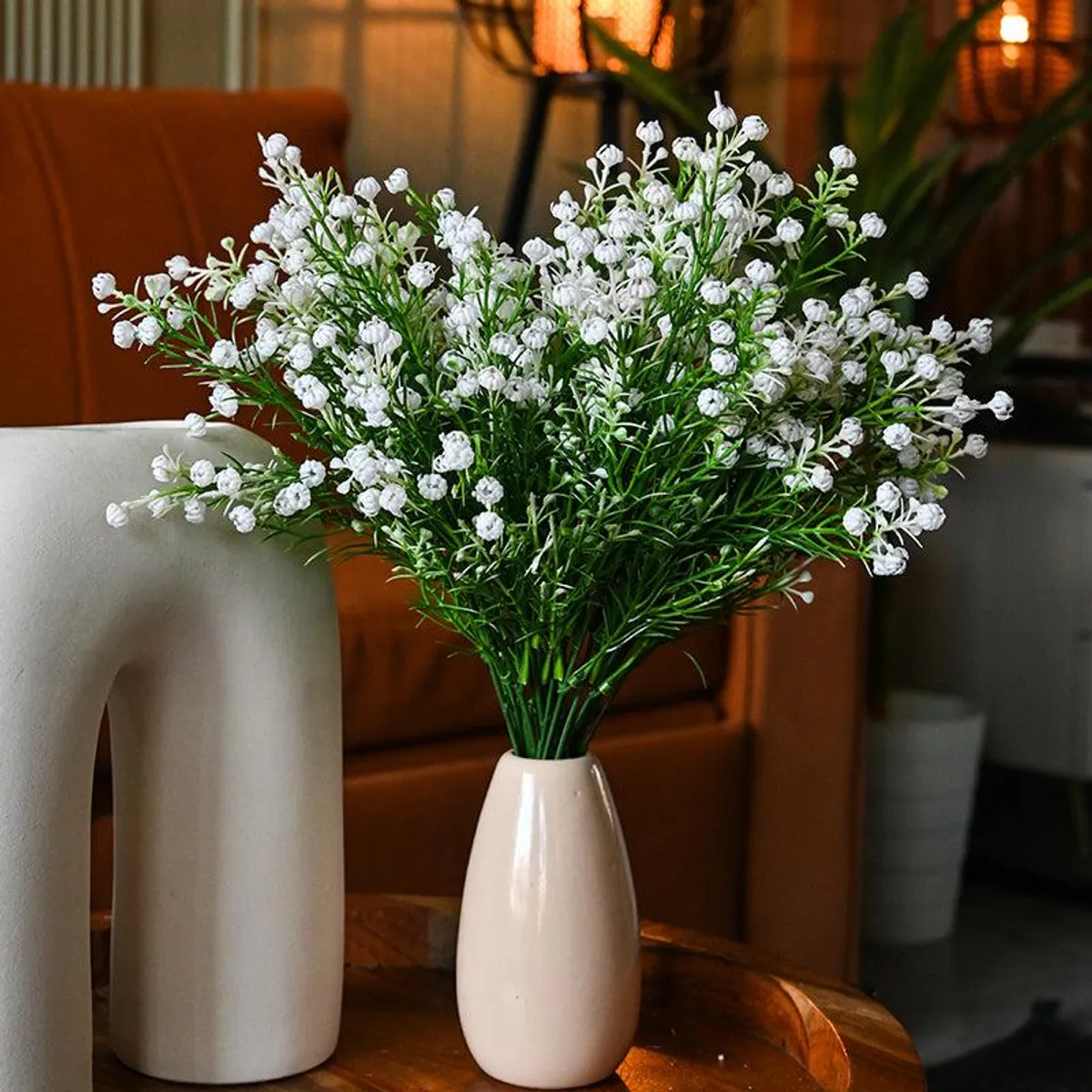 Six white baby breath flower sticks arranged in a small vase on a table