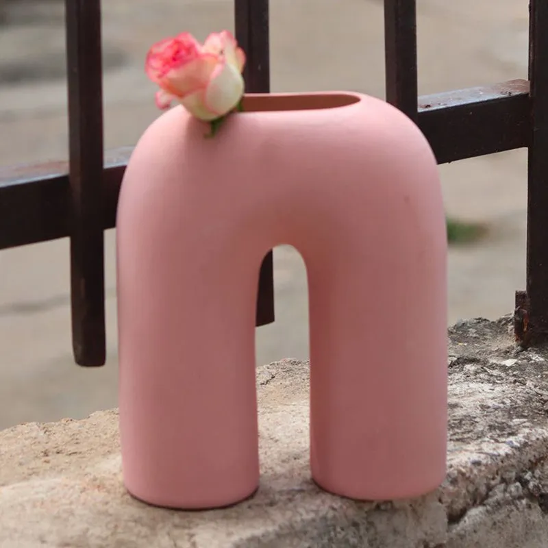 Pink arc-shaped ceramic vase placed by a window ledge
