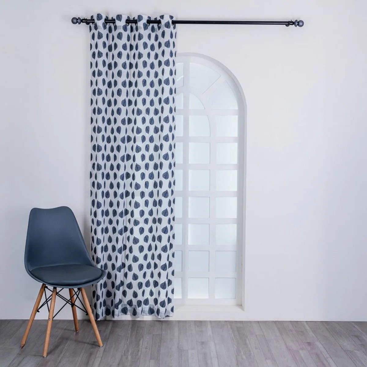 One grey leaf-patterned curtain covering an arched window.