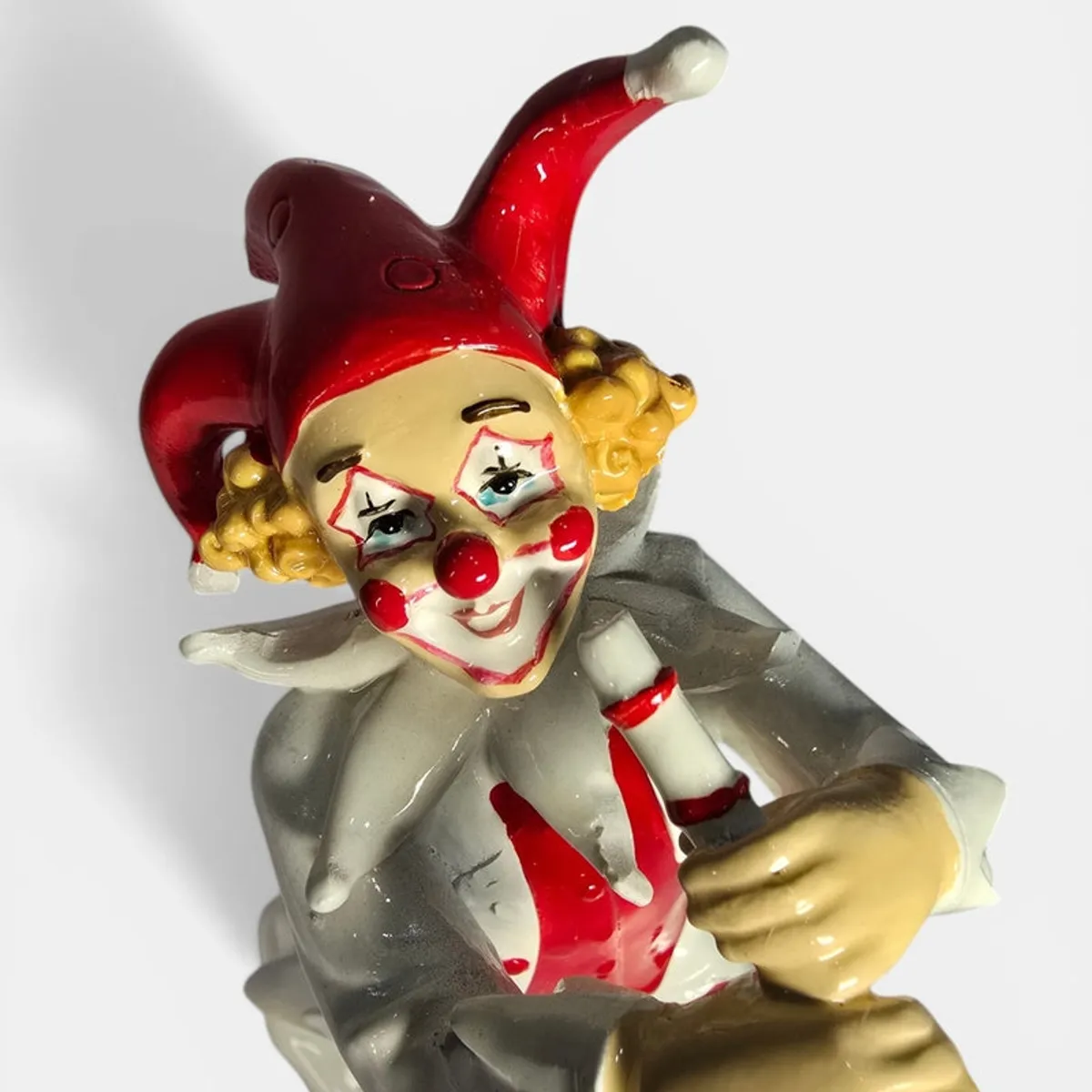 Close-up of clown figurine face with red hat and yellow curls