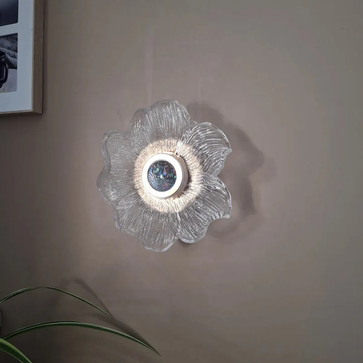 Transparent flower-shaped wall lamp with textured glass petals on a neutral wall