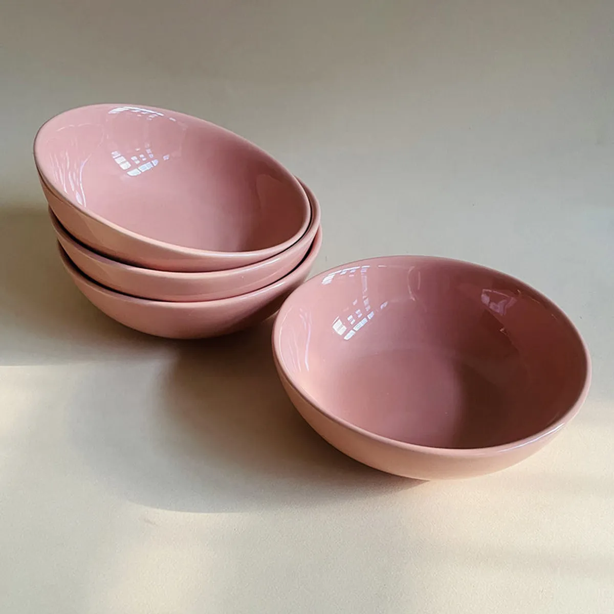 Stacked peach bowls with one bowl placed separately on a neutral surface