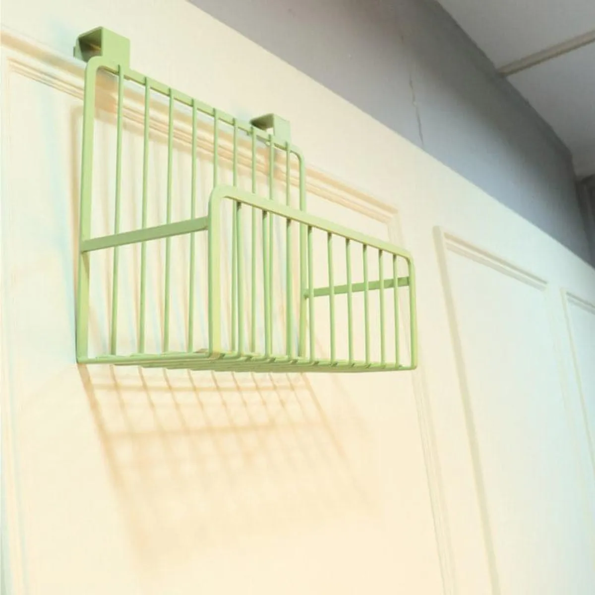 Green metal over-the-door kitchen rack shelf mounted on a white door