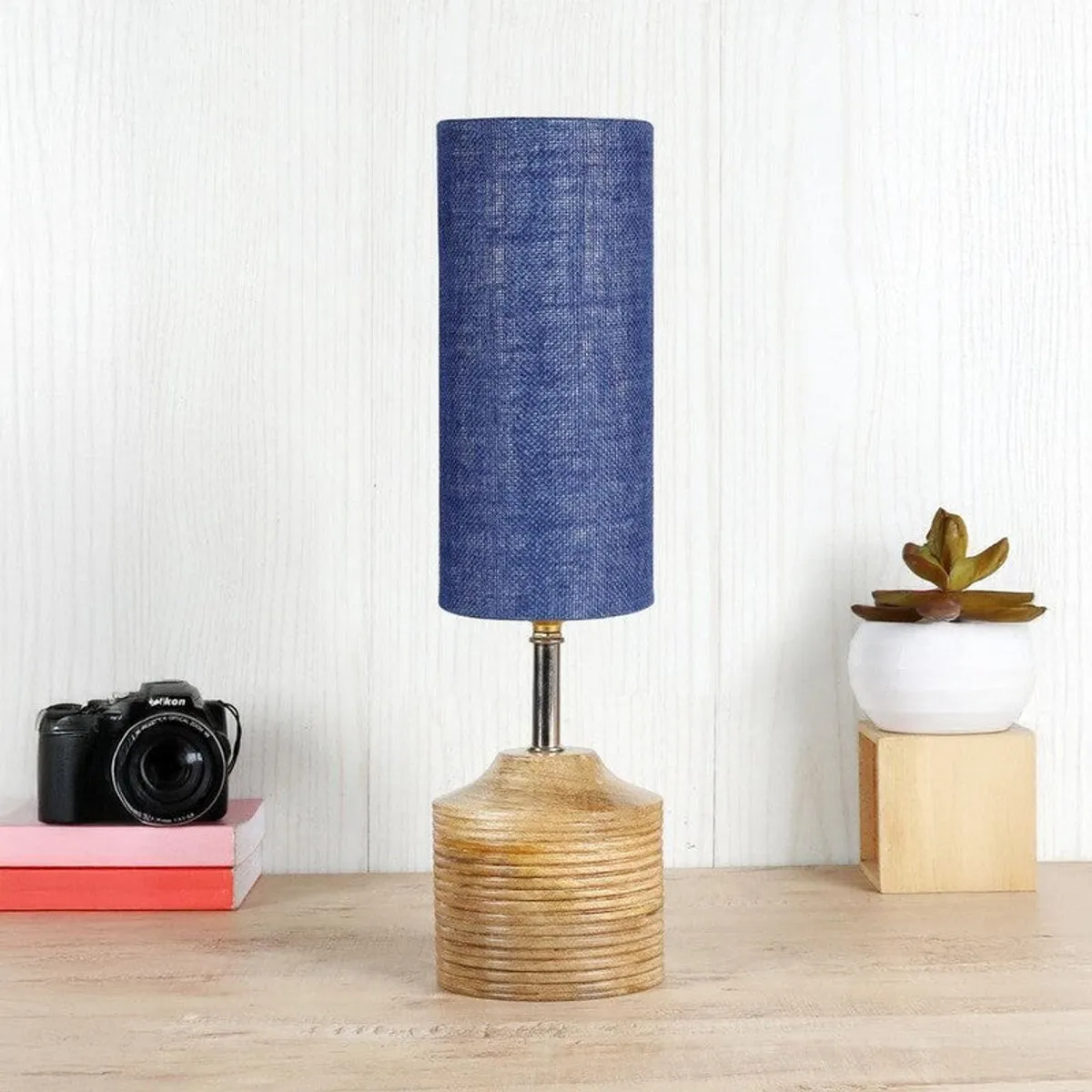 Blue cylindrical table lamp with brown textured base on a wooden surface