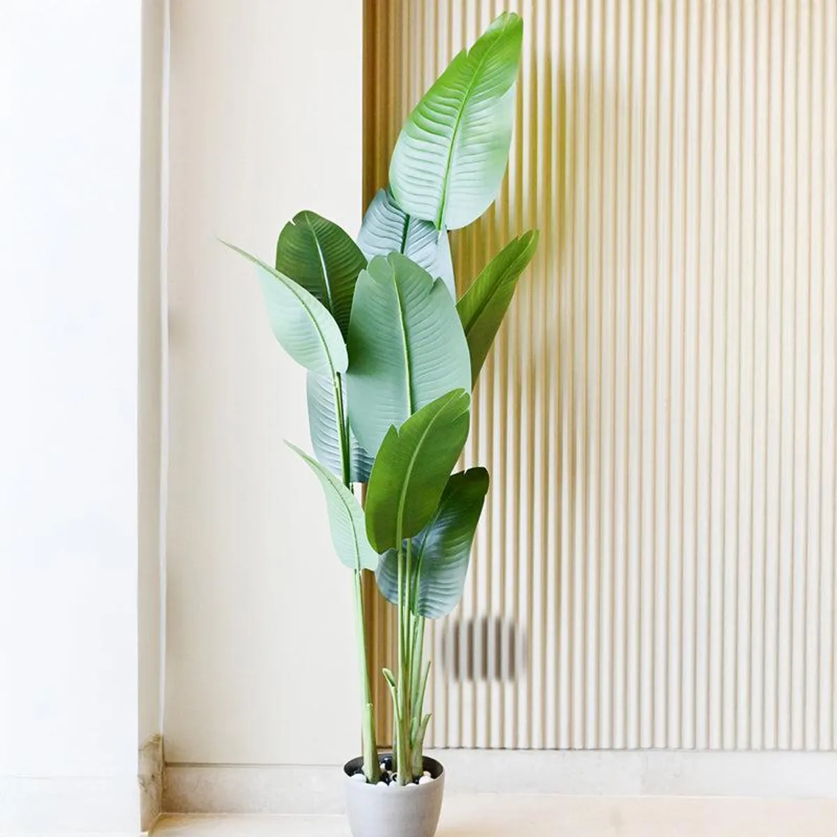 Artificial tropical plant styled indoors beside a fluted wall