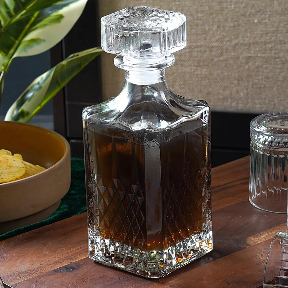 Close view of a transparent decanter with faceted stopper and textured base
