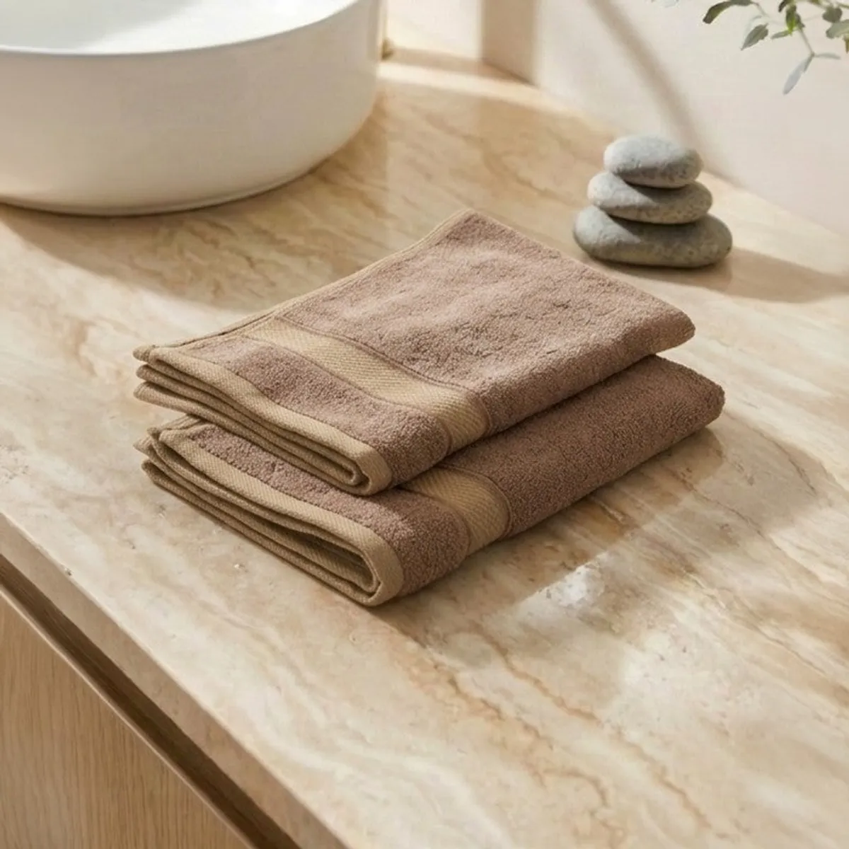 Two folded beige-brown hand towels displayed on a vanity