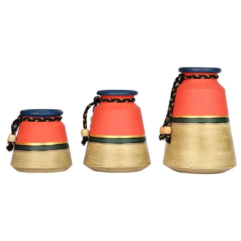 Rear view of three red and beige urn vases with blue rims on a white background