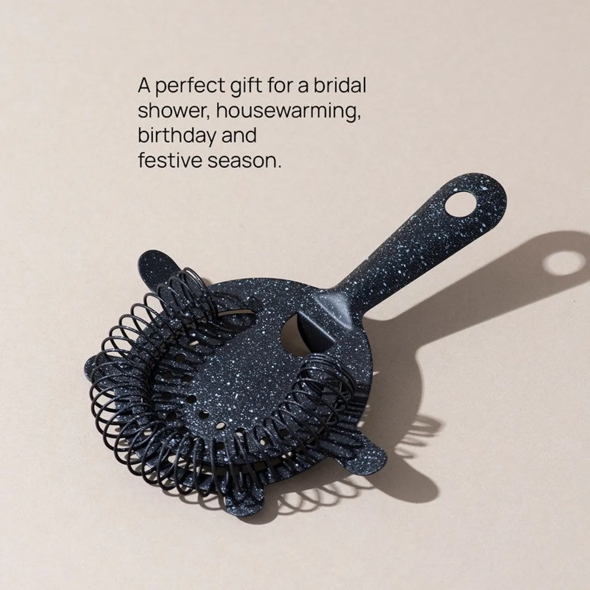 Speckled black cocktail strainer shown on a neutral surface