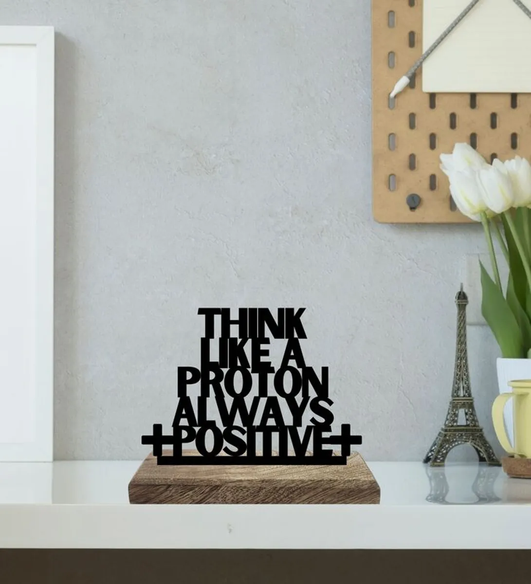 Black typography showpiece on a wooden base styled on a white shelf
