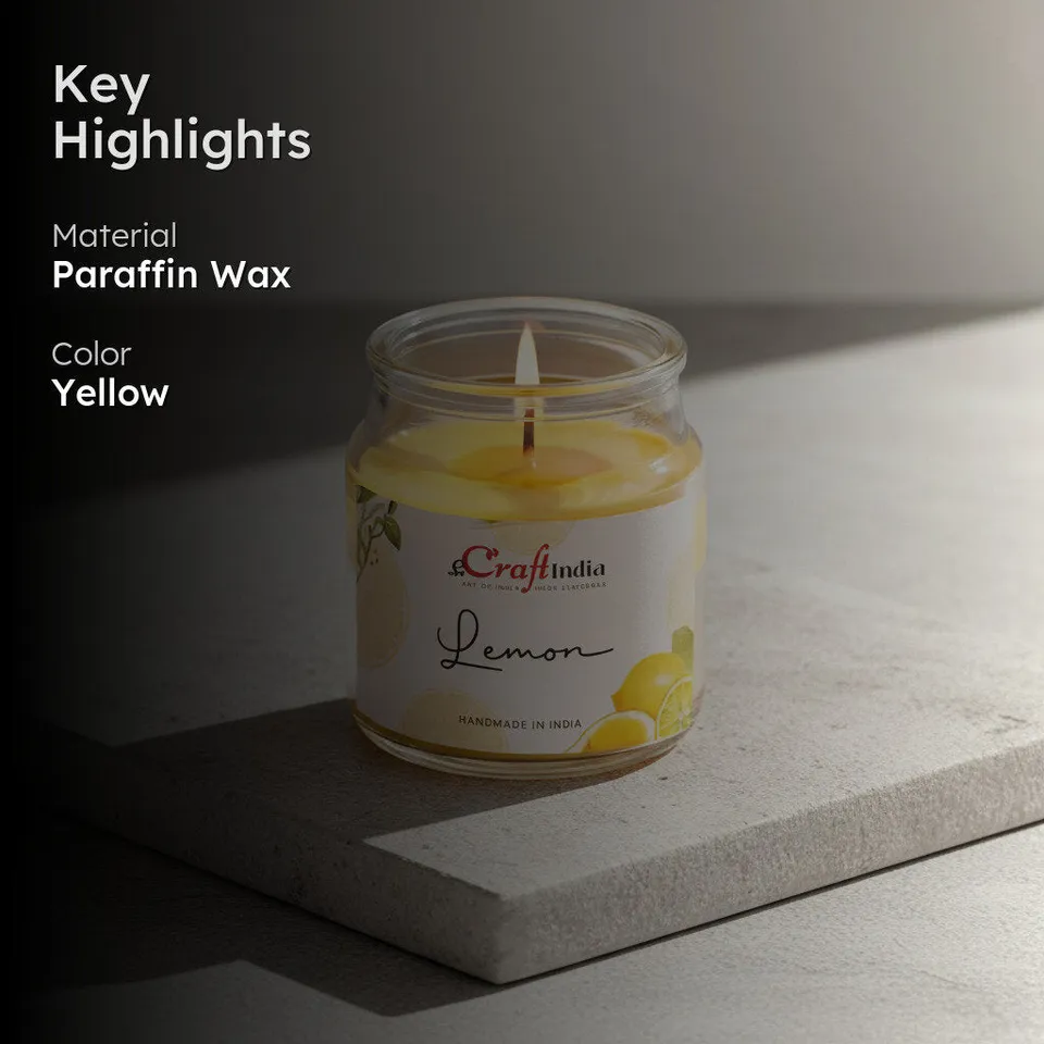 Lit yellow candle in a clear glass jar on a stone surface