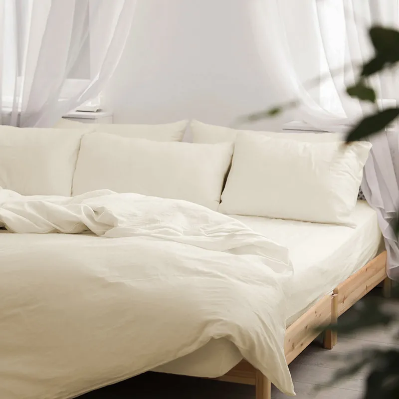 Ivory bedding with matching pillow covers styled on a light wood bed