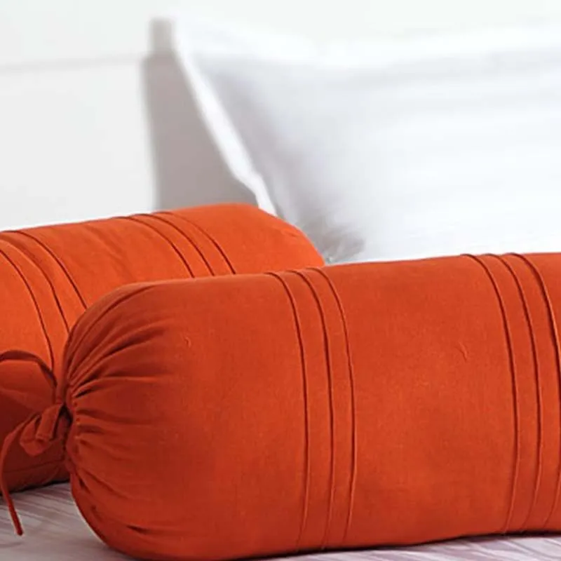 Close-up of orange bolster covers with stitched detailing and tie-up end