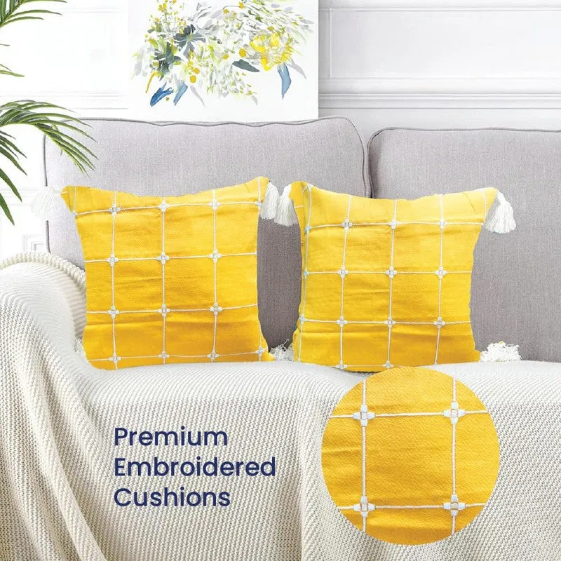 Pair of yellow embroidered grid cushion covers styled on a grey sofa