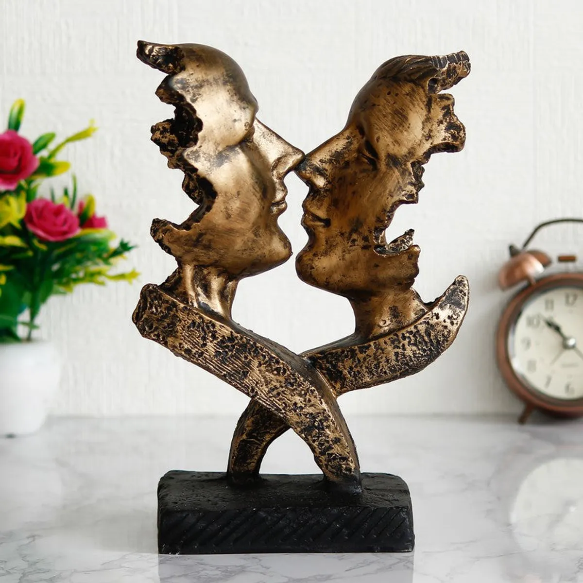 Gold-toned abstract face figurine showpiece on a black base in a styled setting
