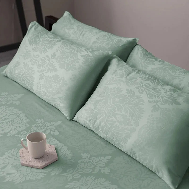 Close view of sage green pillow covers and floral bedsheet