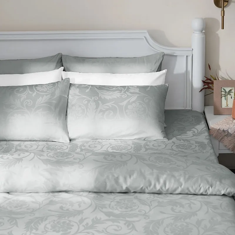 Light grey floral duvet cover styled on a bed with matching patterned pillows