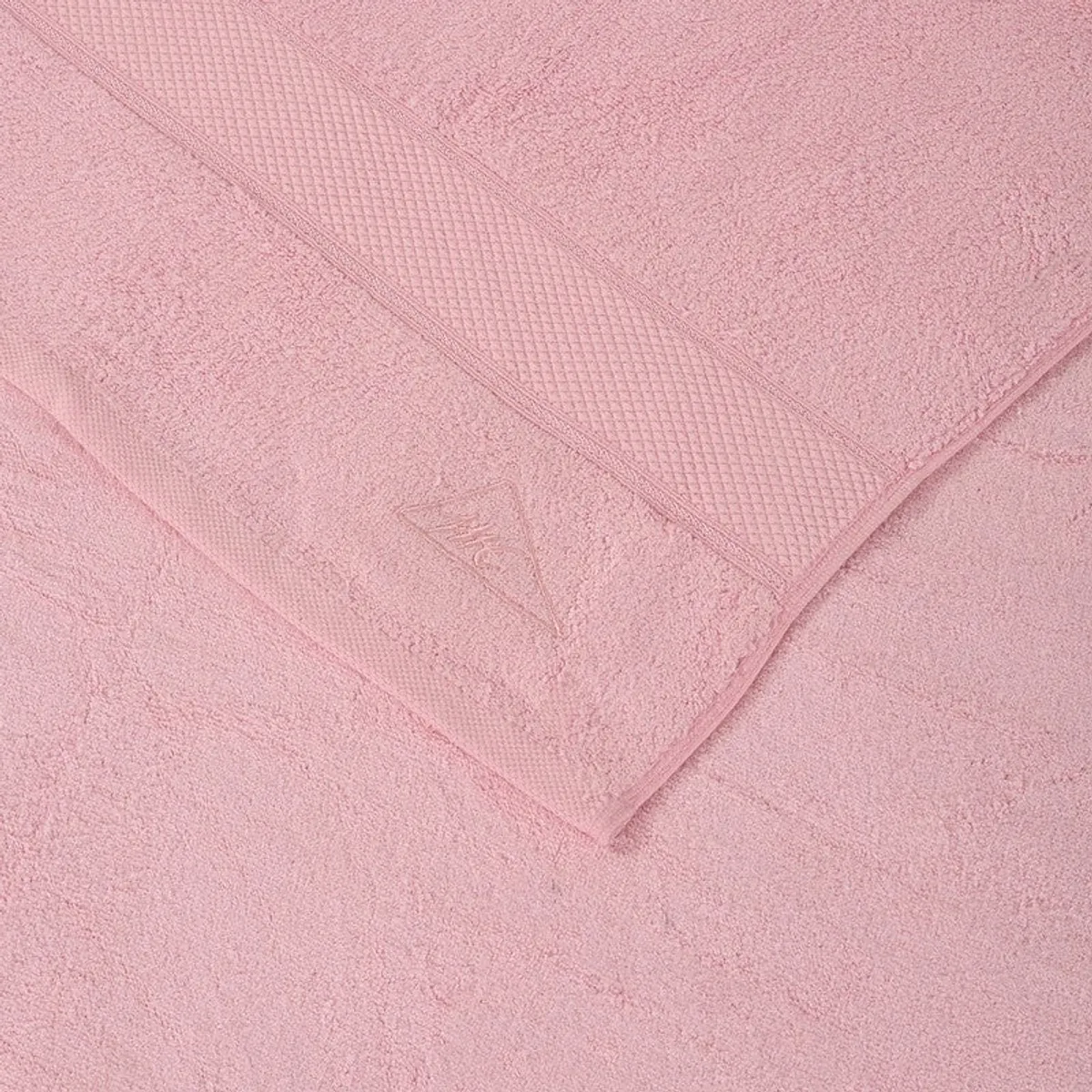 Close-up of the light pink towel showing its soft pile and subtle border detail