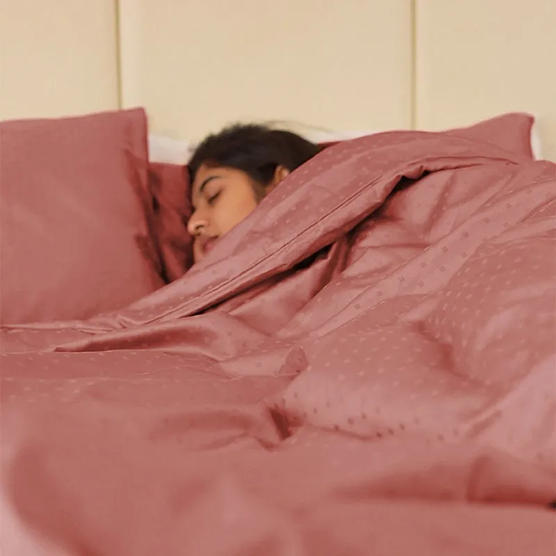 Person relaxing under a pink-brown dotted duvet cover