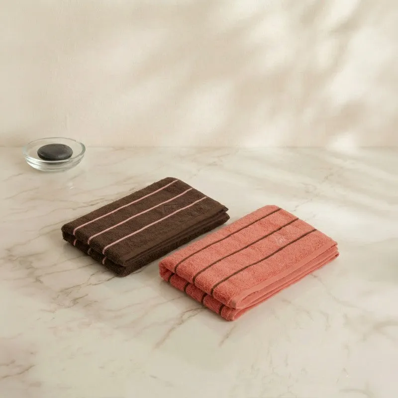 Folded brown and orange striped bath towels on a light marble surface