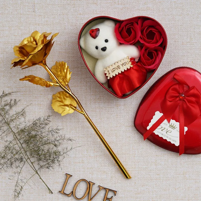 Heart-shaped red gift box with teddy and red roses beside a gold rose stem