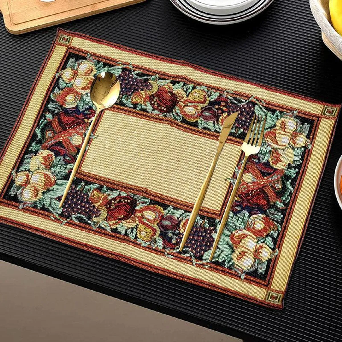 One woven placemat styled with gold cutlery on a dark tabletop