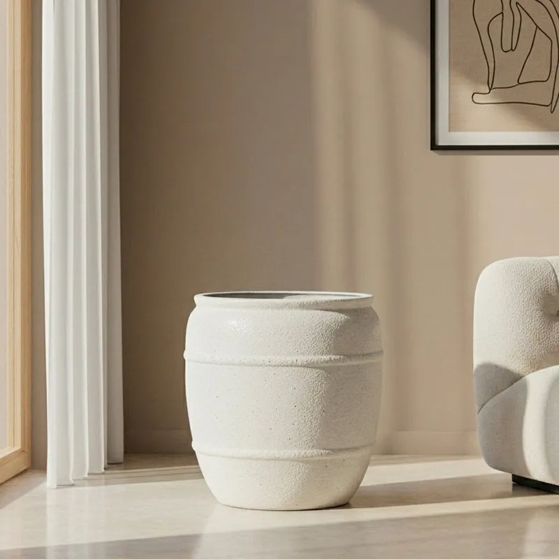 Off-white cylindrical floor planter shown empty beside a sofa