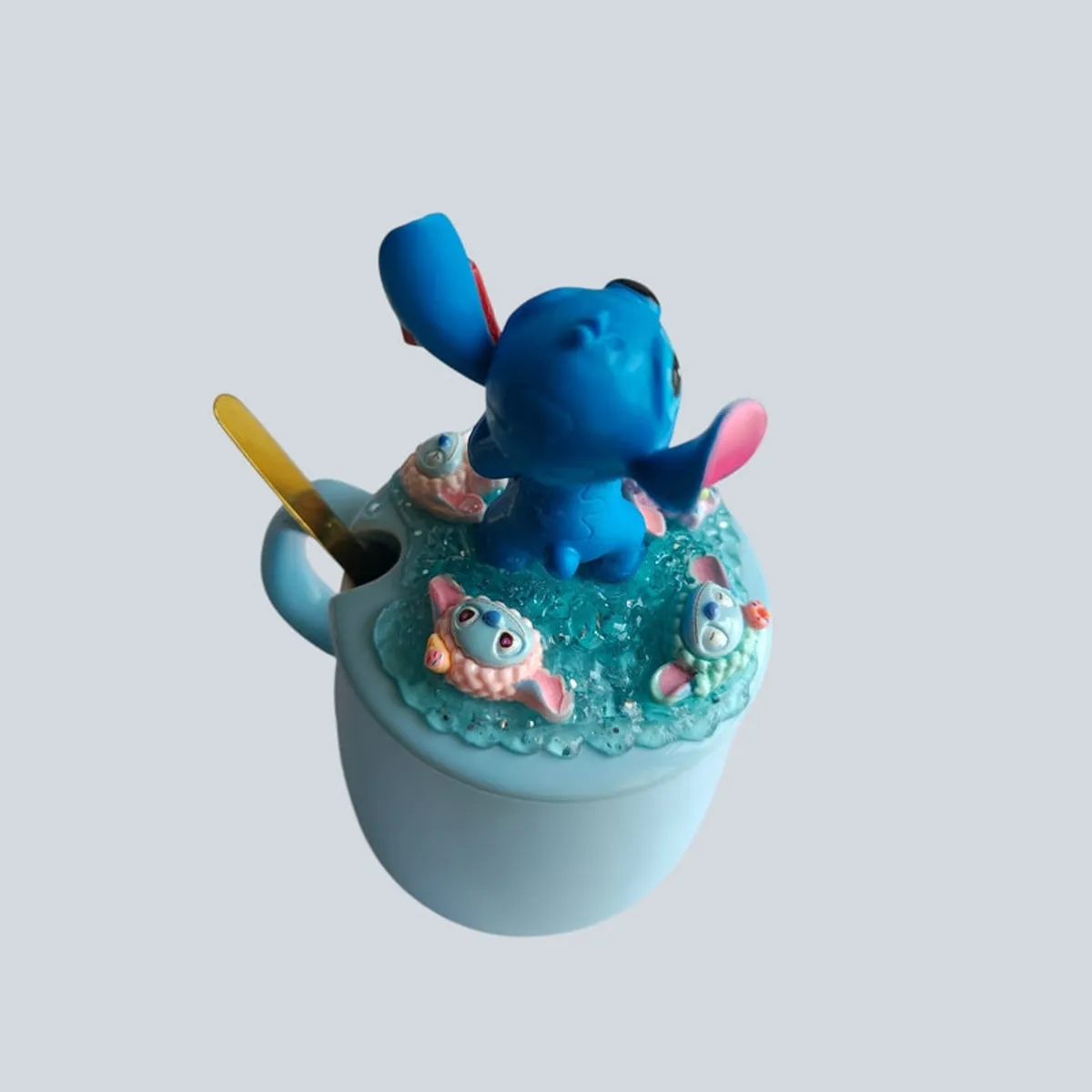 Top angled view of blue mug with textured decorative lid and Stitch figure