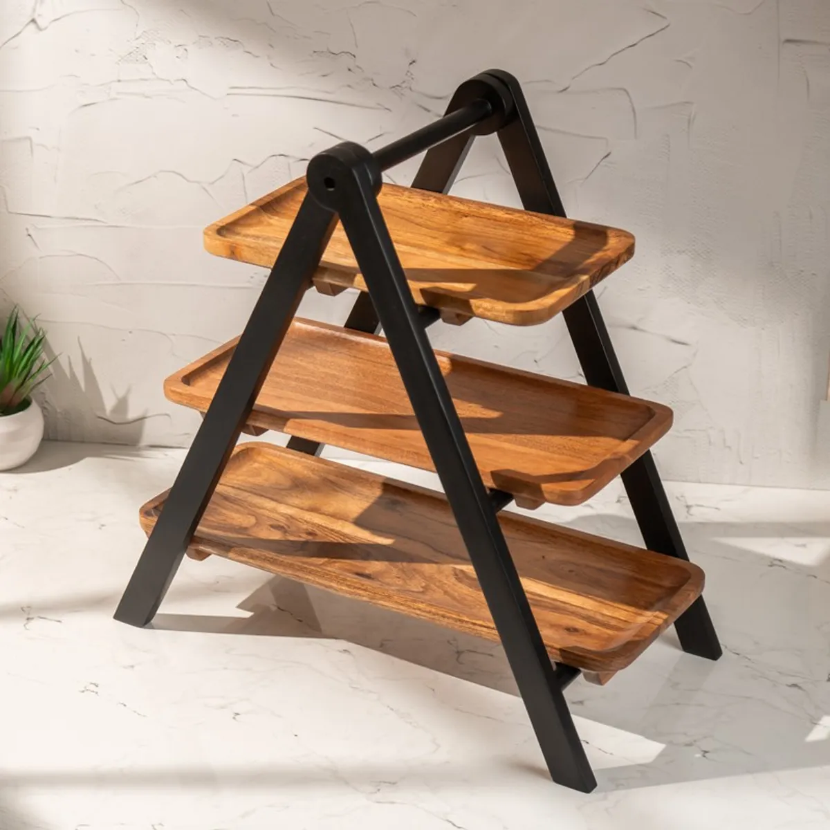 Angled view of a three-tier wooden serving stand with black frame