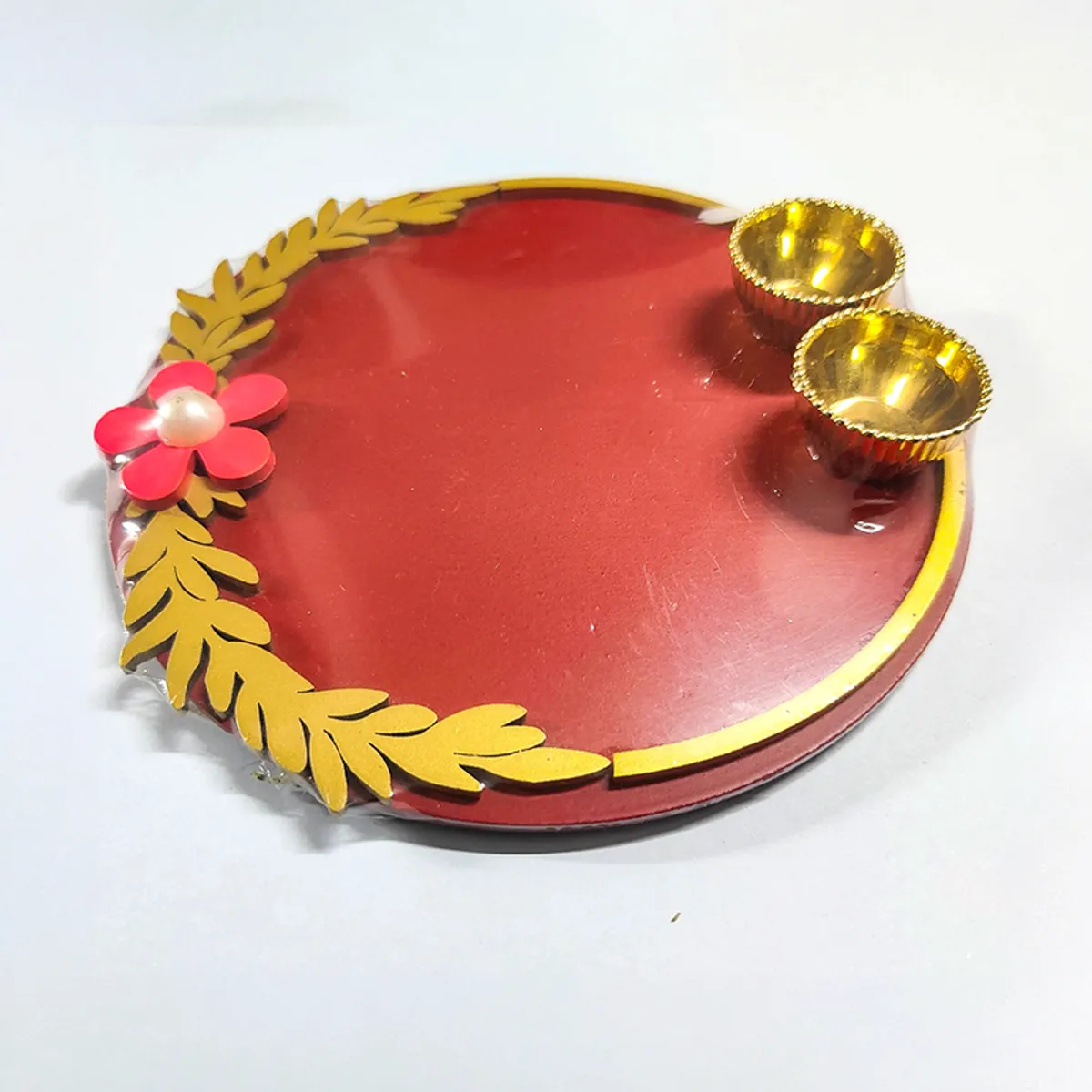 Maroon round pooja thali with gold detailing, flower accent and two bowls