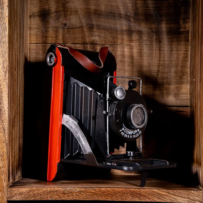Black and red vintage camera showpiece displayed inside a wooden shelf
