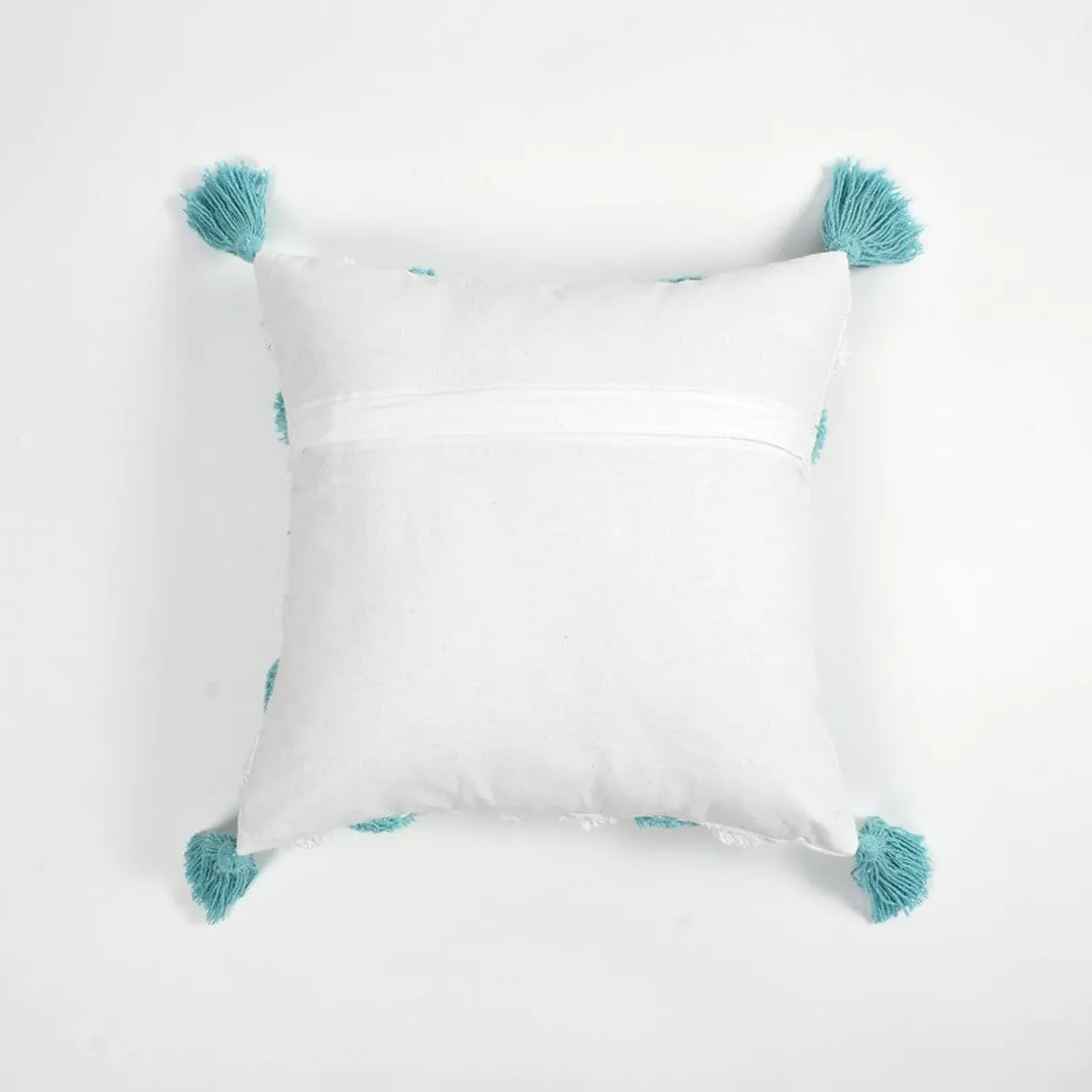 Back view of a white cushion cover showing its zip closure and blue corner tassels