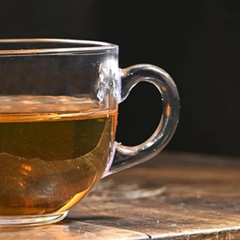 Close-up of a transparent glass tea cup handle and tea