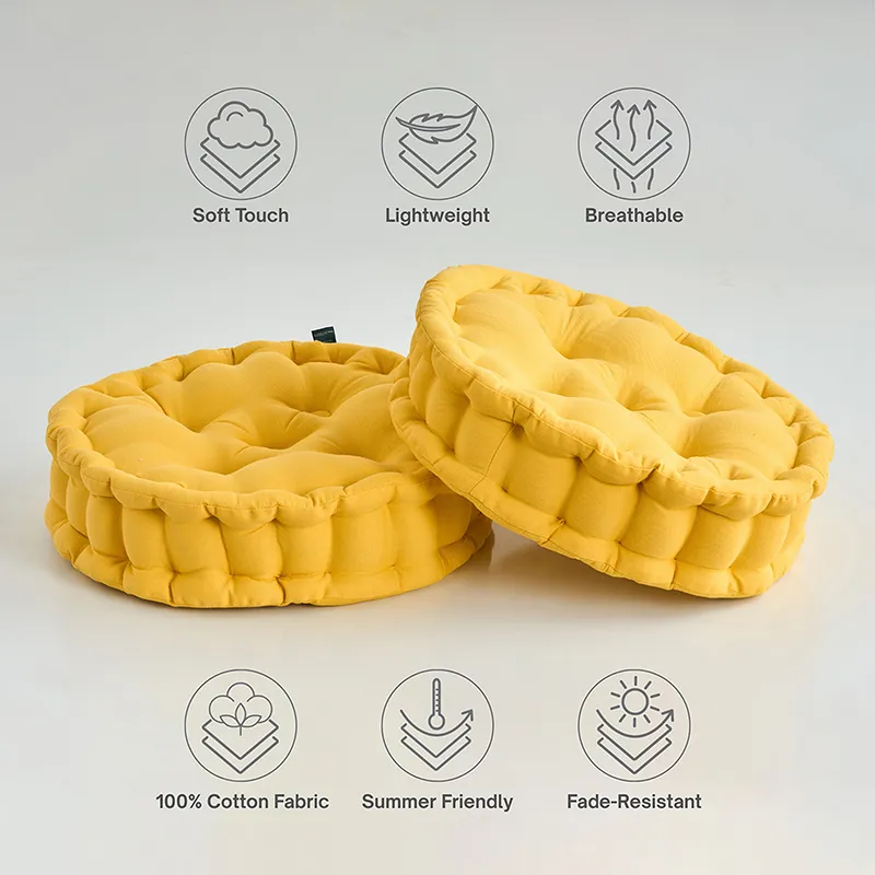 Two round mustard yellow floor cushions on a plain background