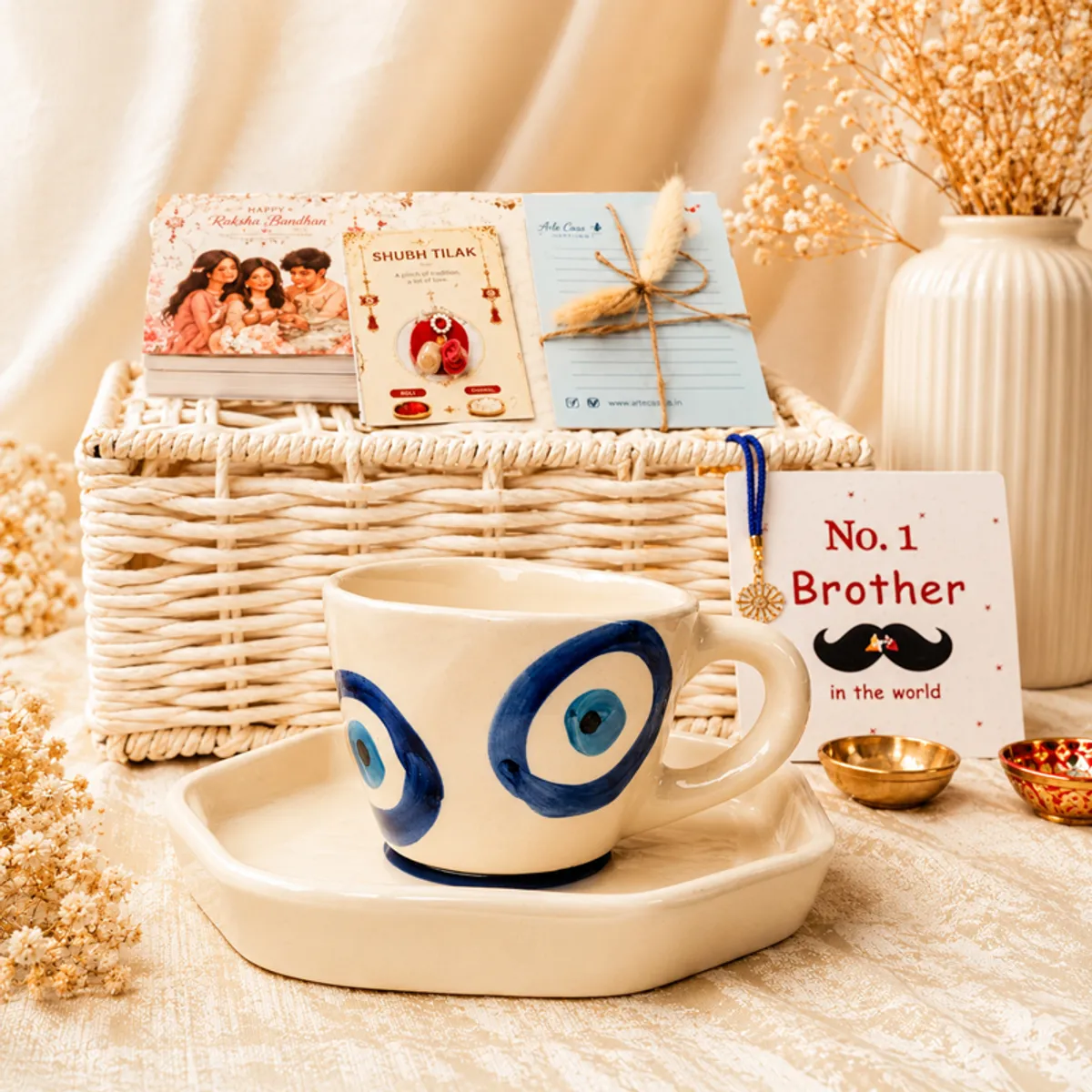 Blue evil eye mug with saucer displayed in front of the hamper and greeting cards