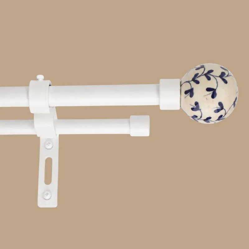 Close-up of white double curtain rod with blue floral round finial and bracket