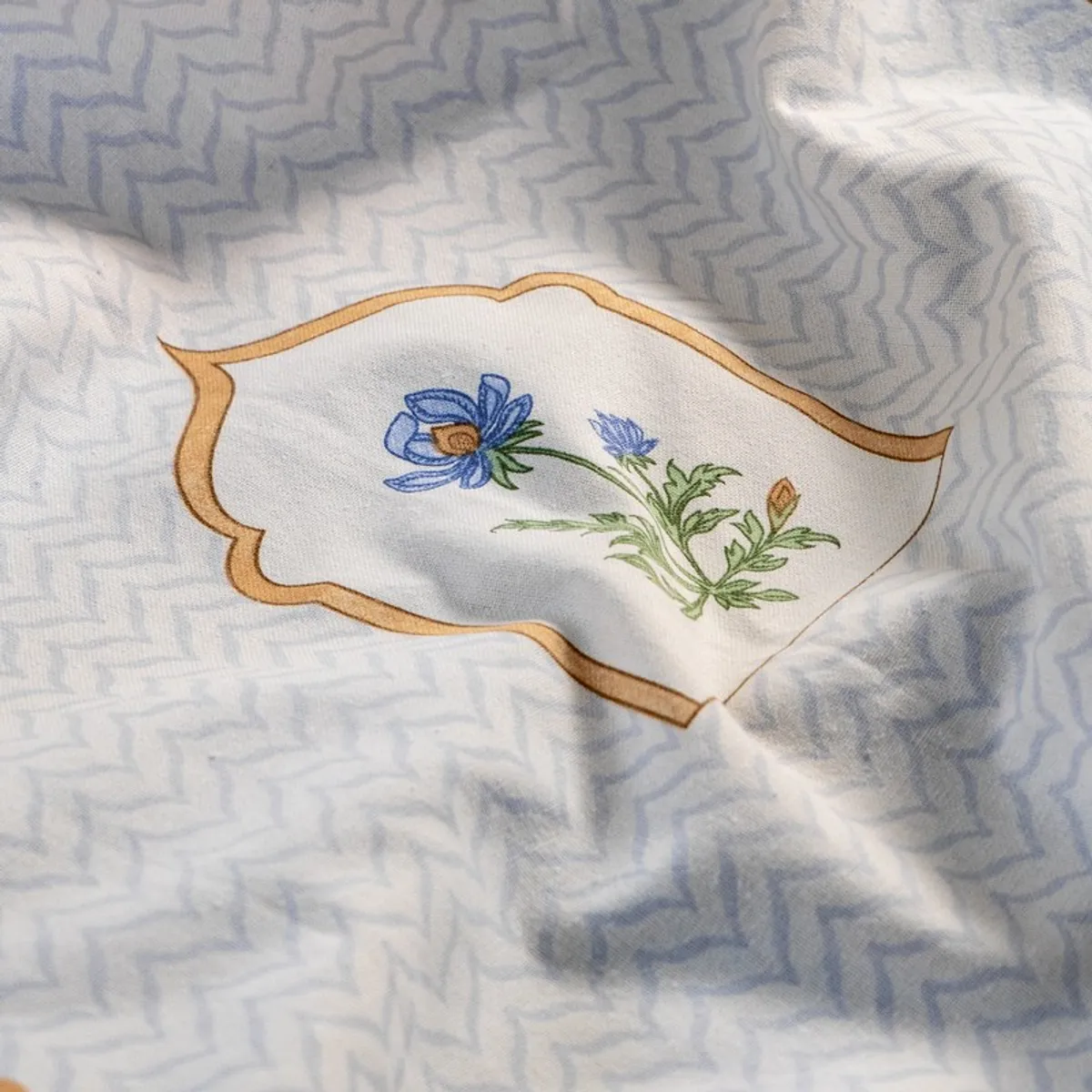 Close-up of blue flower motif on a white patterned curtain
