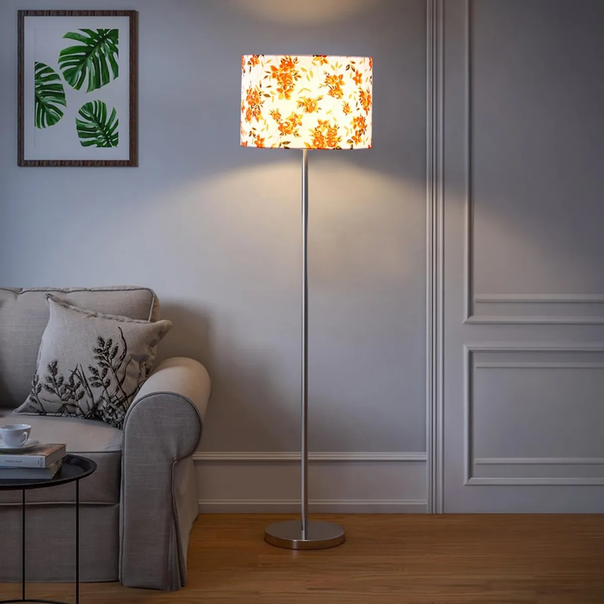 Floral shade floor lamp lit beside a grey sofa in a classic living room