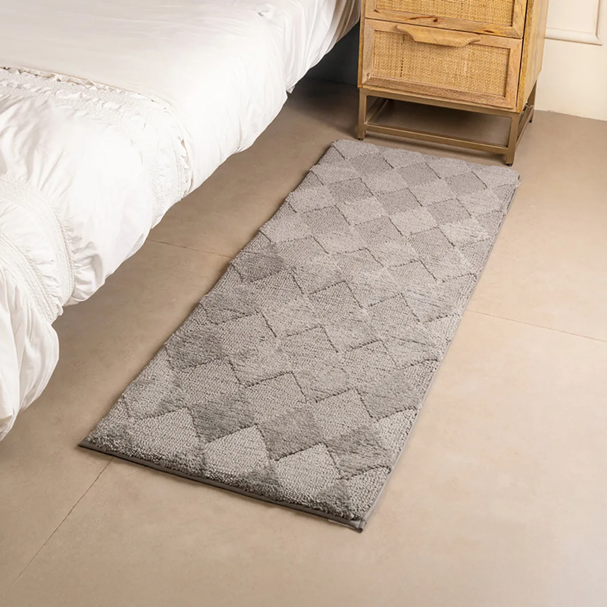 Grey geometric runner rug placed beside a bed in a bedroom setting