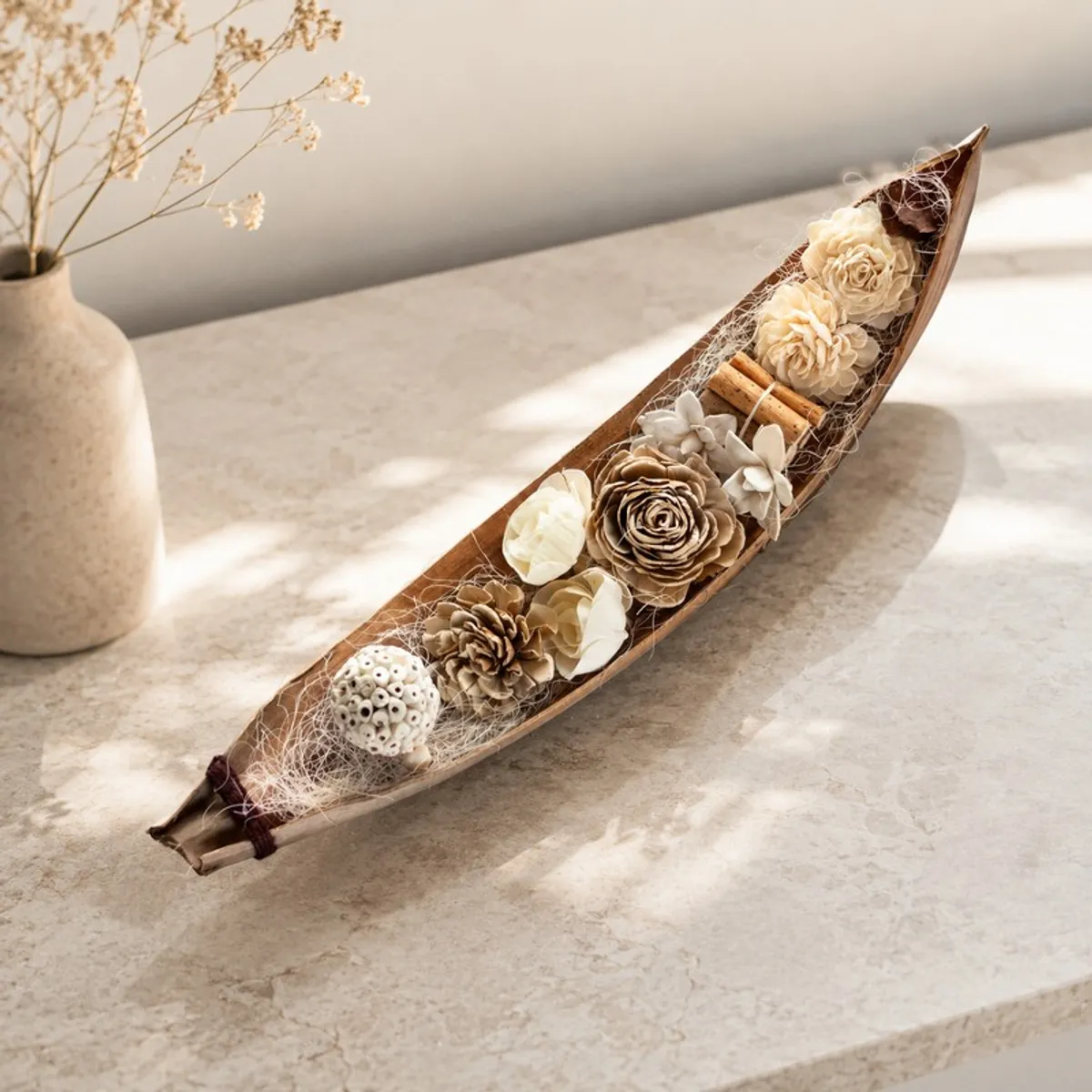 Elongated cream and brown floral arrangement on a pale tabletop