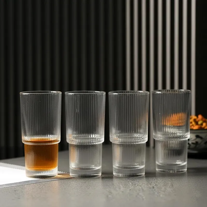 Four clear ribbed glasses standing in a row on a tabletop