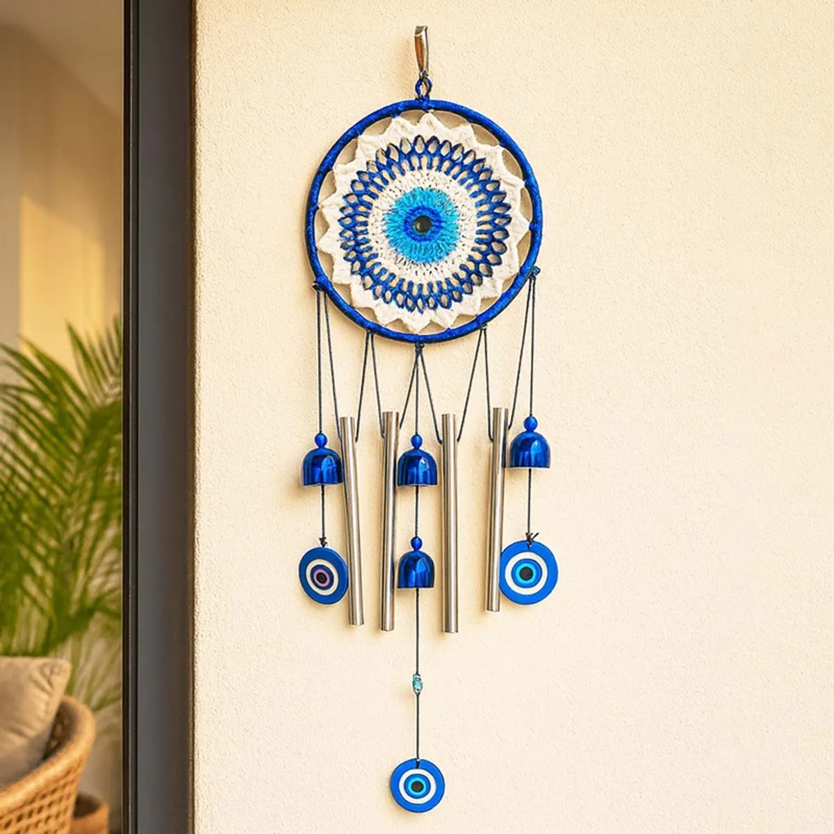 Blue and white evil-eye wind chime displayed against a light wall
