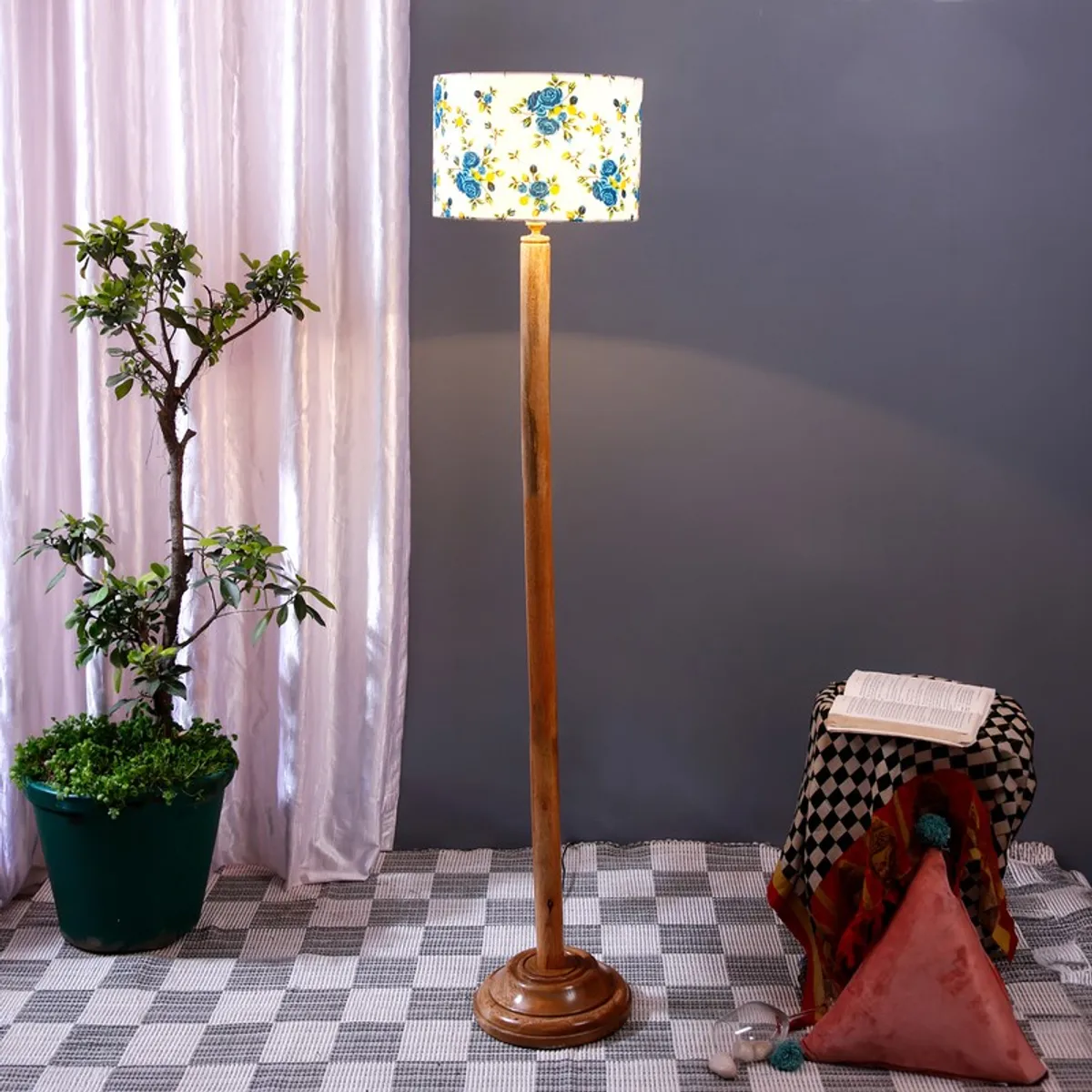 Lit wooden floor lamp with blue floral shade in a styled room corner
