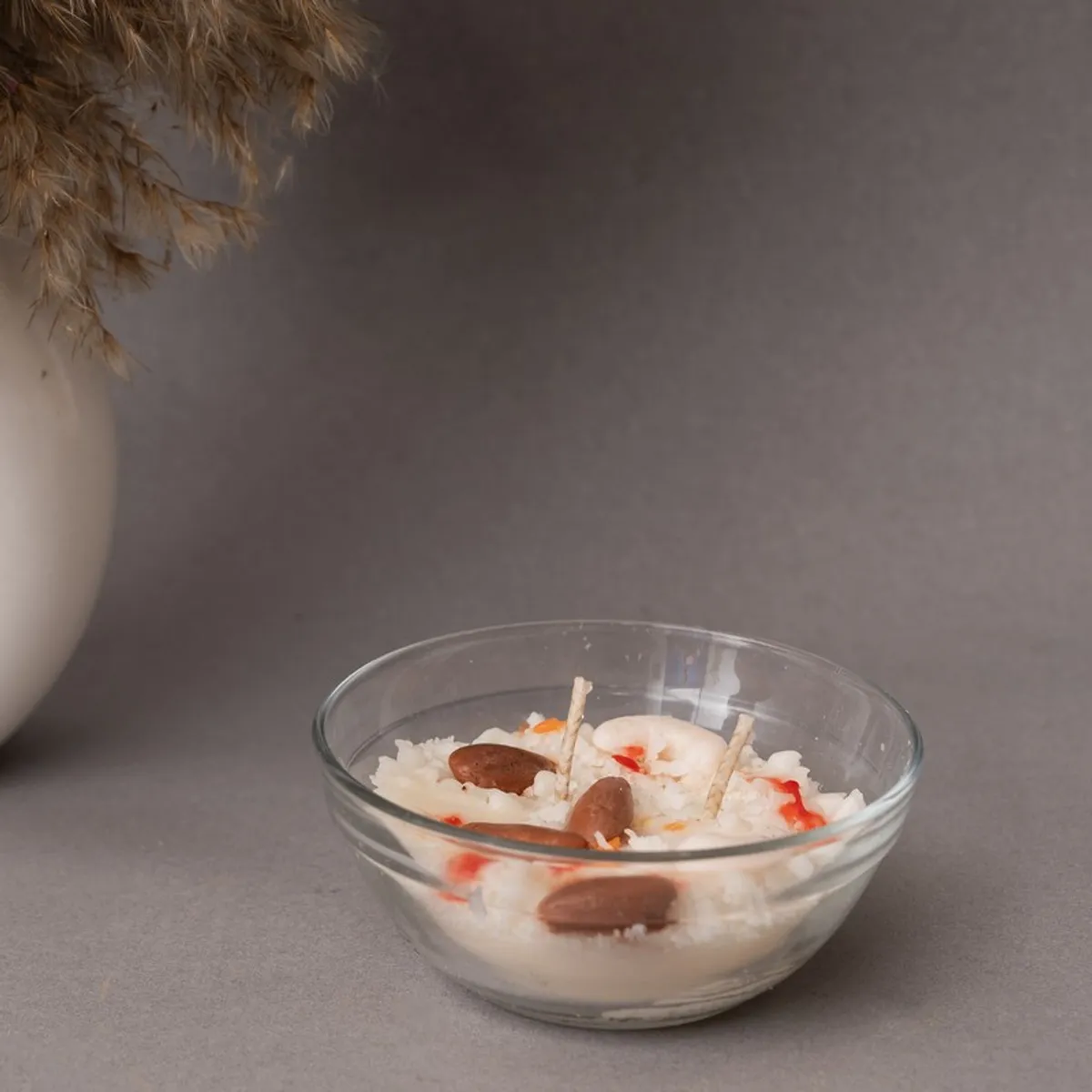 White dessert-inspired candle in a clear glass bowl against a grey background