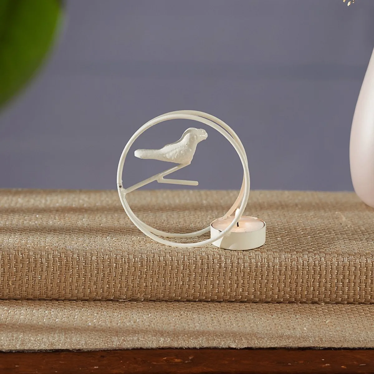 Close-up of a white circular bird-inspired tealight holder with a tealight