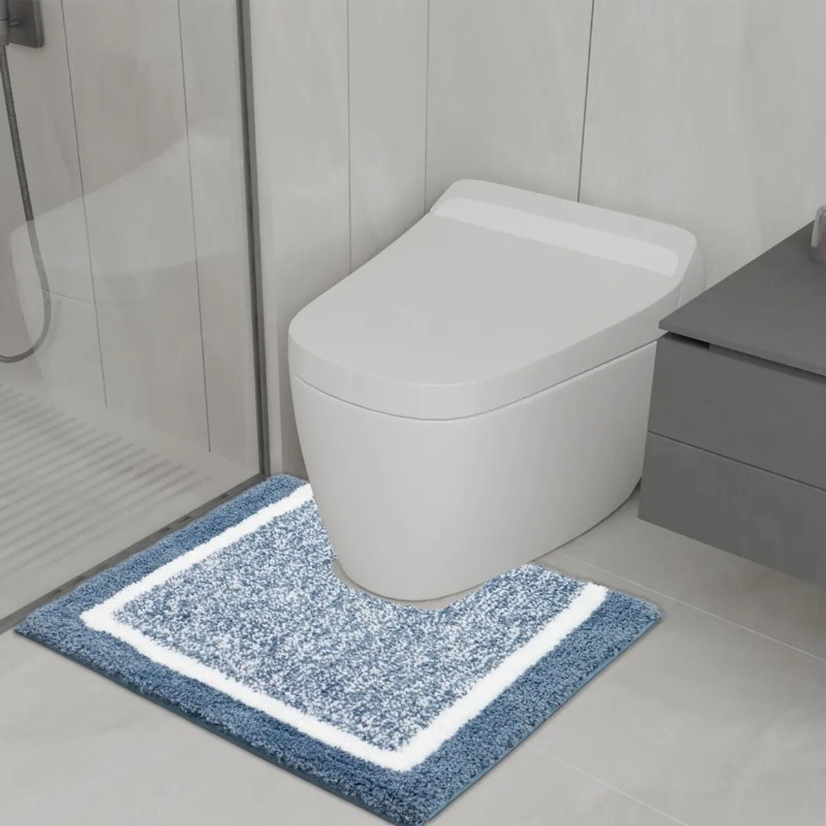 Blue and white bath mat positioned in front of a modern toilet