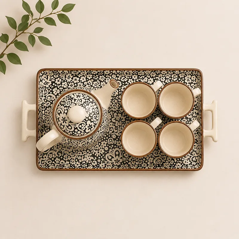 Top view of black-and-white patterned teapot, four cups and serving tray