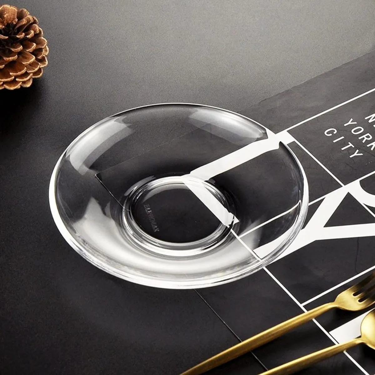 Single clear glass saucer on a dark surface