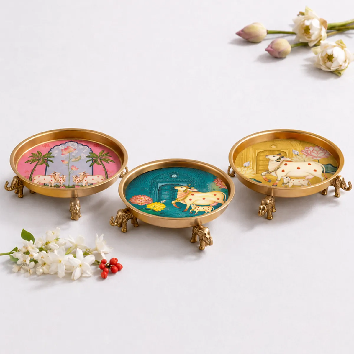 Three round elephant-themed urlis shown in pink, teal and gold designs